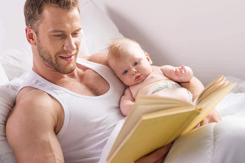father reading a book with baby