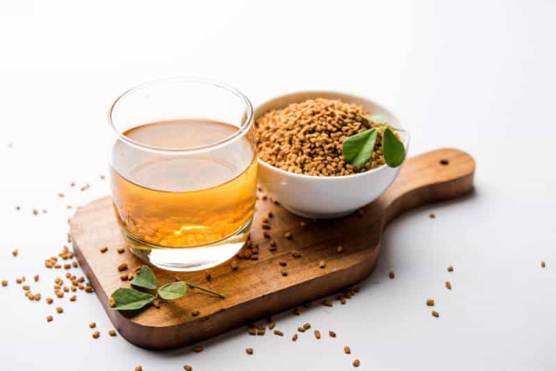 Fenugreek tea with seeds on wooden plate