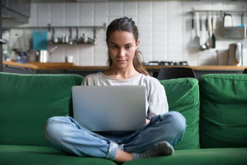 woman sitting on sofa and using laptop at home