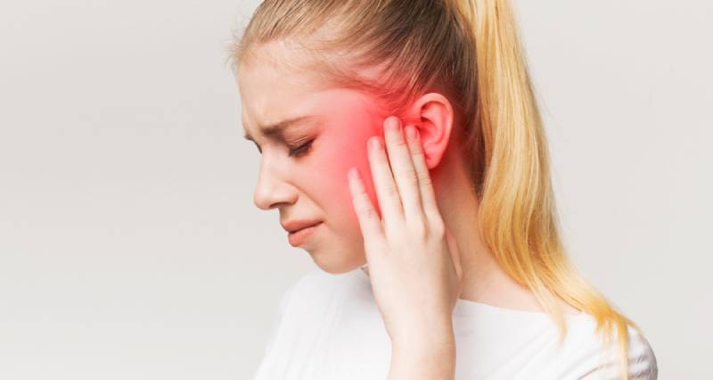 Profile of blond, sick female having ear pain while holding it