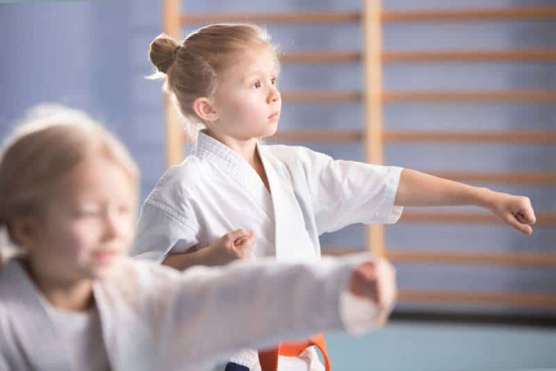 Young girls in kimono exercising during an extra-curricular karate class