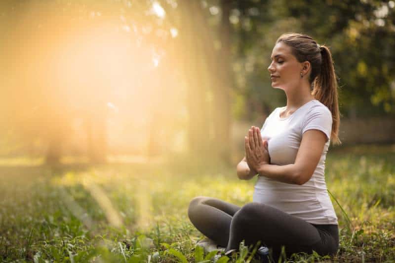 Pregnant woman meditating in nature during sunset