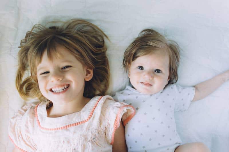 Sisters smiling while lying on bed together