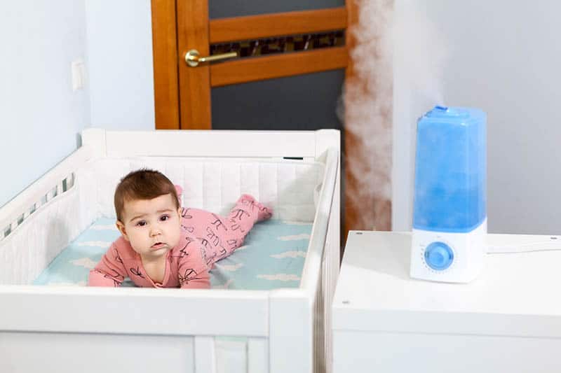 baby in crib with humidifier in room