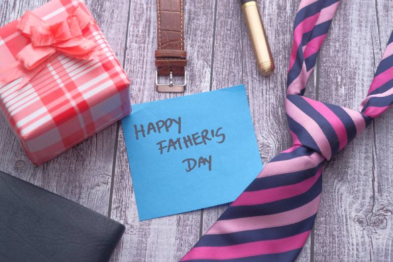 Happy Father's Day inscription with tie and watch on wooden background