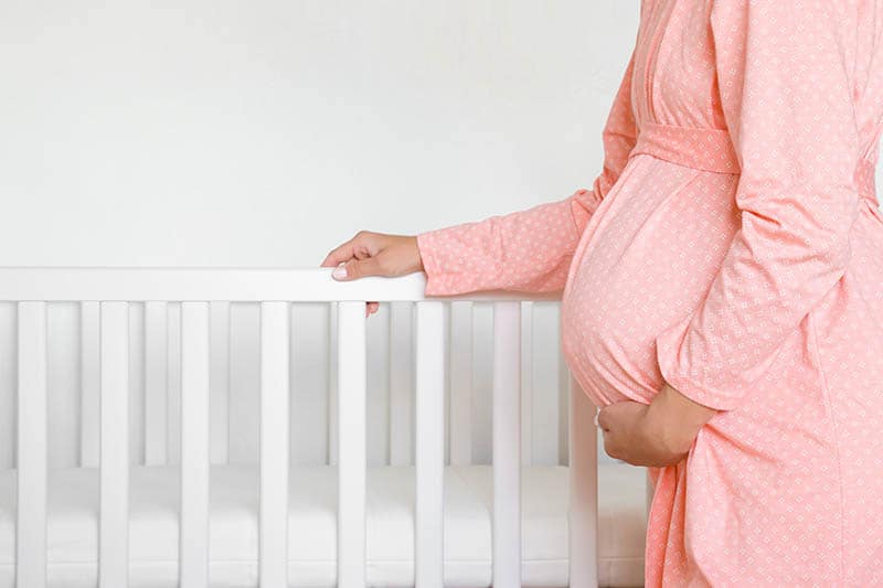 pregnant woman standing by the baby crib