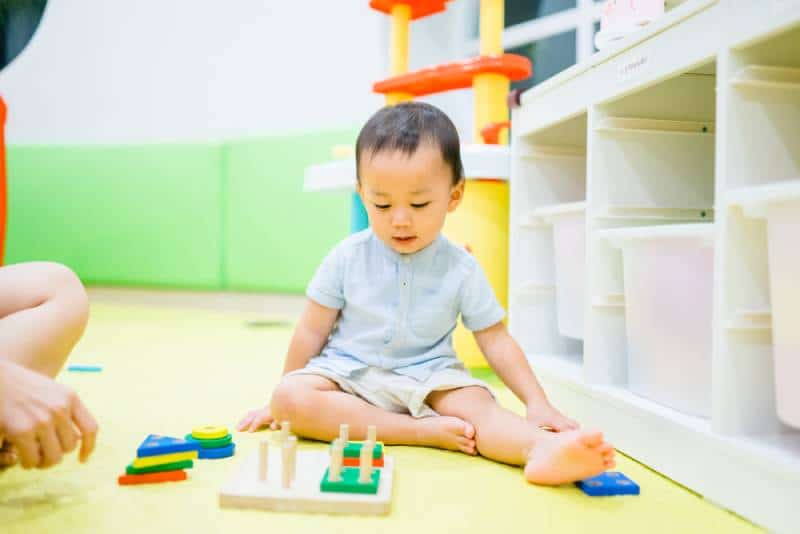 2.5 years old baby boy playing with lots of wooden toys block with mother