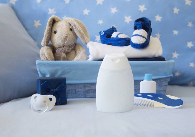 baby background with blue basket, plush toy, bootees, pacifier, toiletries and gift box