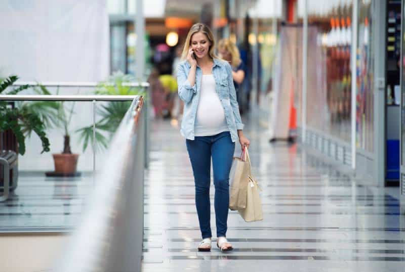 Blond pregnant woman in shopping center making phone call