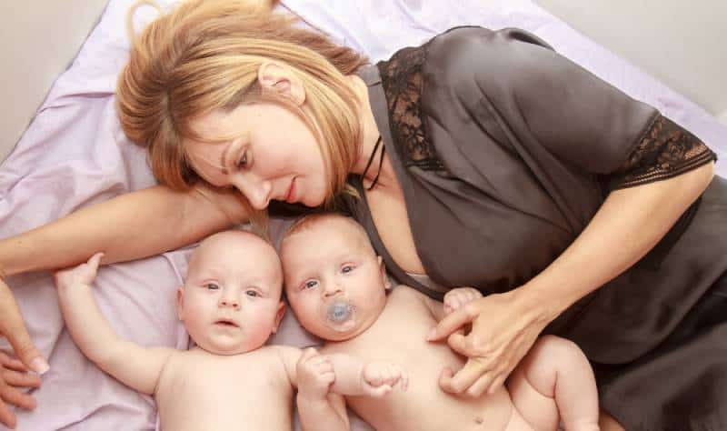 Happy woman in bed with her cute twins