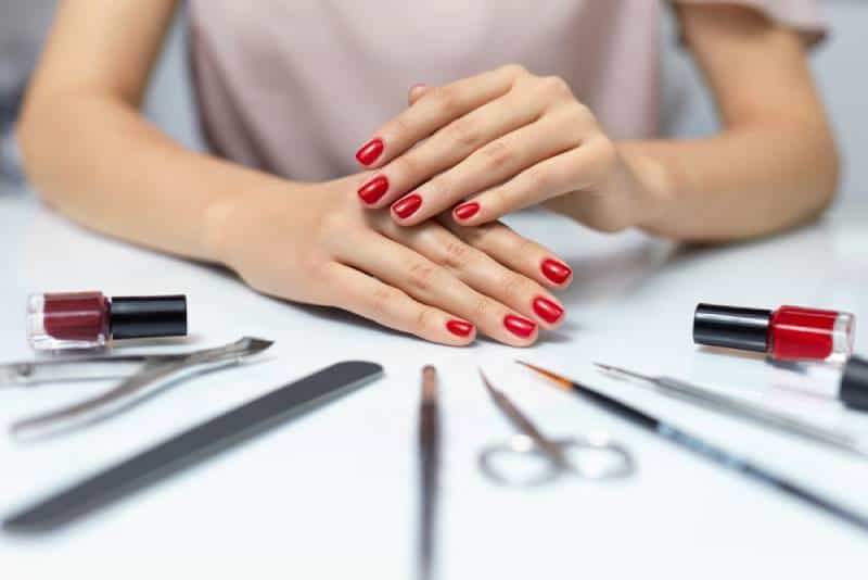 Woman hands showing red nail polish in a home nail salon