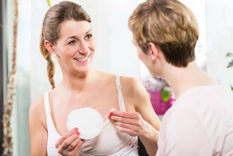 Woman in white using comfortable plastic breast shells inside bra for collecting excess breast milk