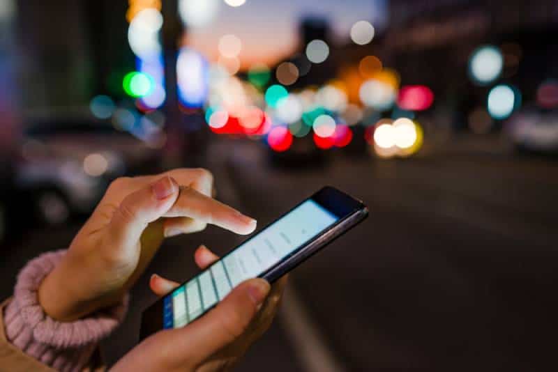 Close-up of woman's hand using phone in night time on street
