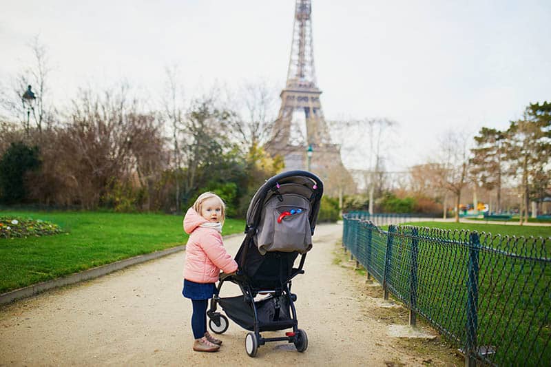 baby girl in France with stroller in front of the Eiffel Tower 