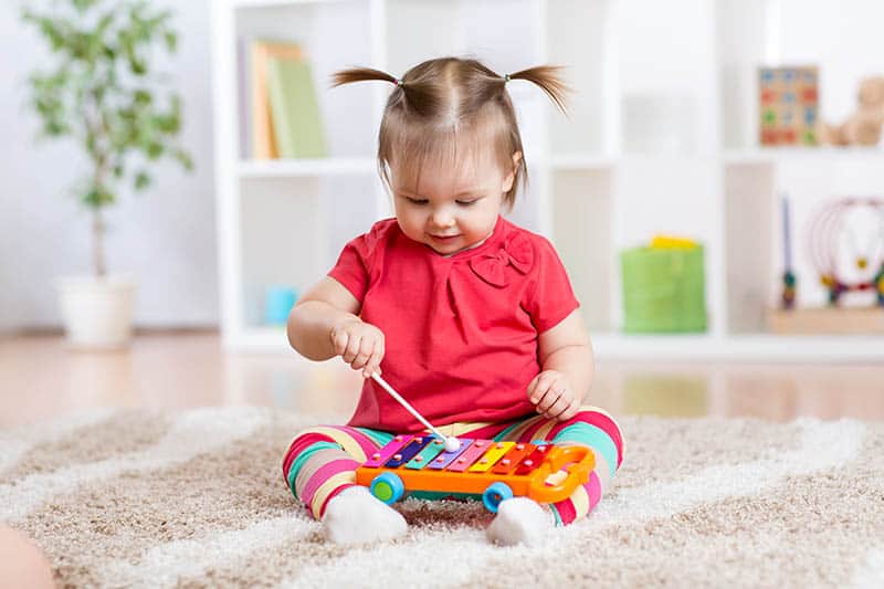 cute baby girl playing with musical instrument