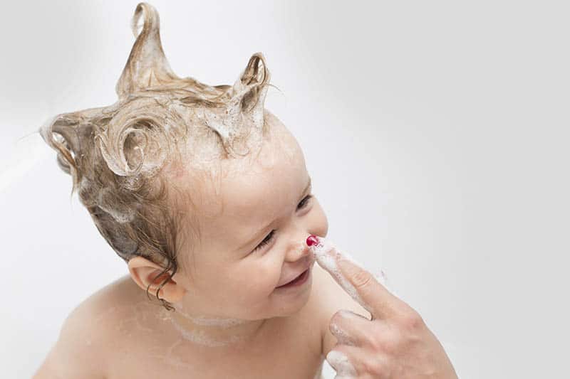 baby smiling while taking a bath mother touching his nose