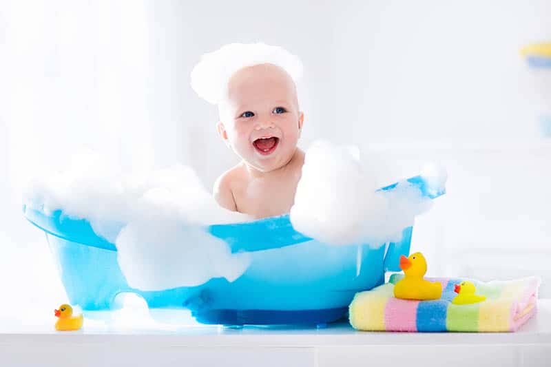 happy kid taking a bath with baby shampoo