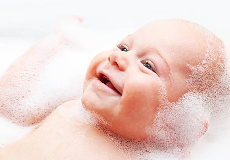 closeup portrait of smiling boy taking a bath in a bath tub