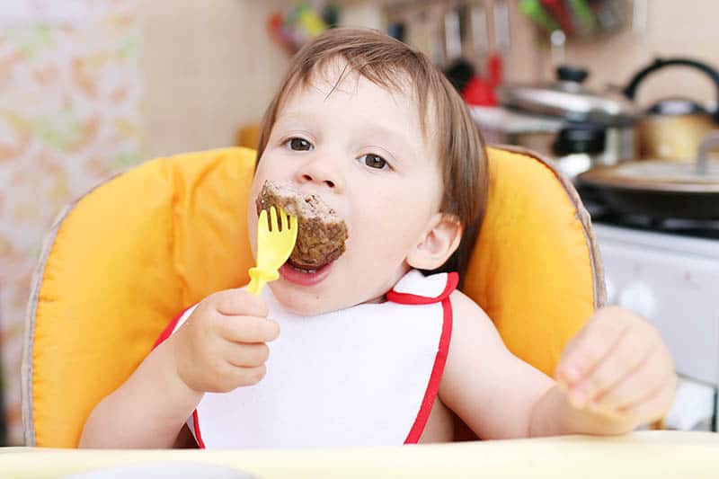 baby toddler boy eating meat 
