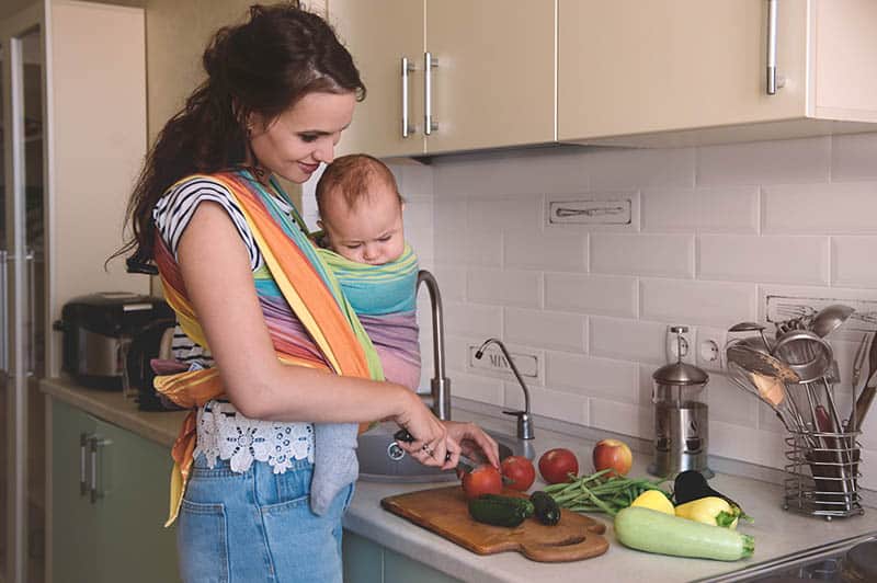 woman with baby making dinner