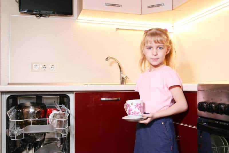 adorable blond girl helping to unload dishwasher 