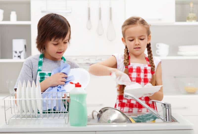 Boy and a girl washing dishes together in the kitchen
