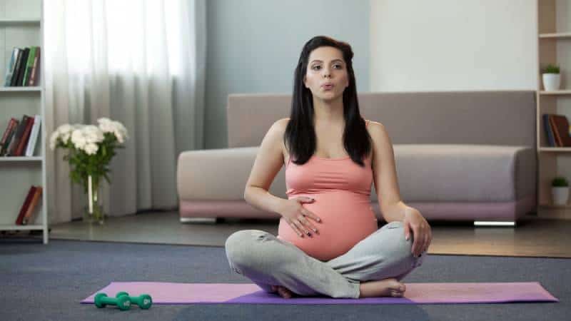 Pregnant woman doing breathing exercise at home