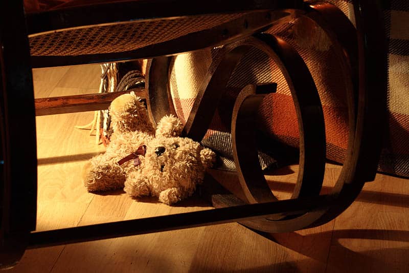 teddy bear lost under rocking chair