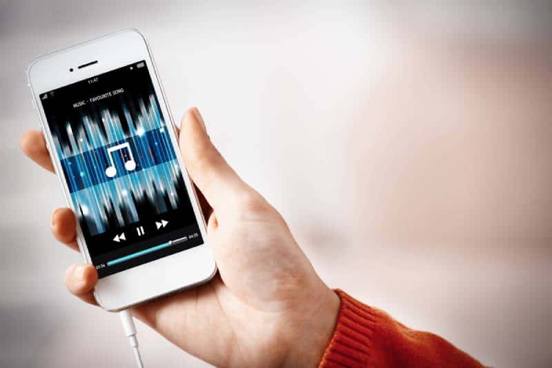 Music smartphone in female hand, on home interior background