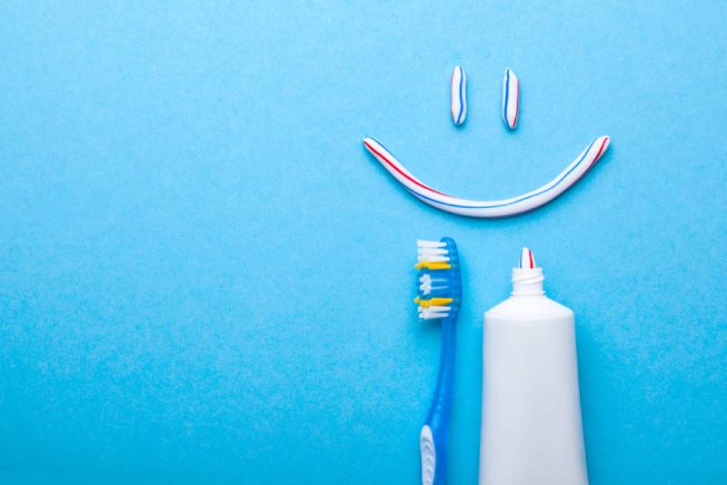 Toothbrush and Tooth-paste in the form of face with a smile on a blue background