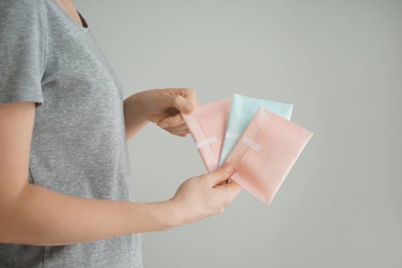 Woman holding menstrual pads on grey background