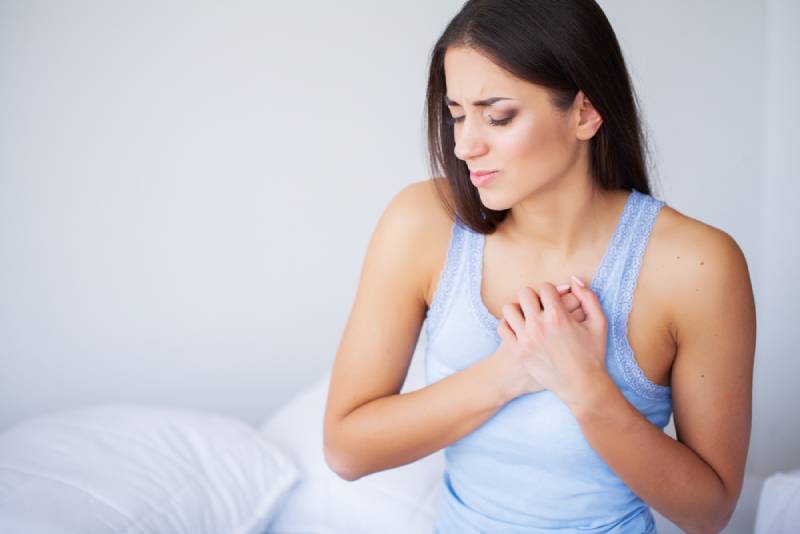 Woman with pain in breasts sitting on bed