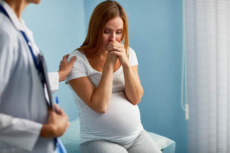 pregnant woman with baby in distress visiting the doctor
