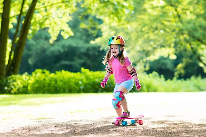 girl riding a skateboard with safety 