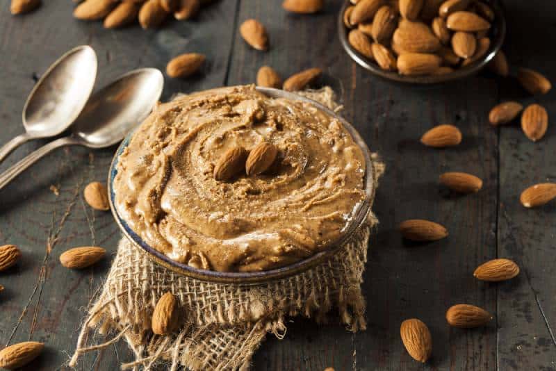 Raw Organic Almond Butter with almonds on wooden Background