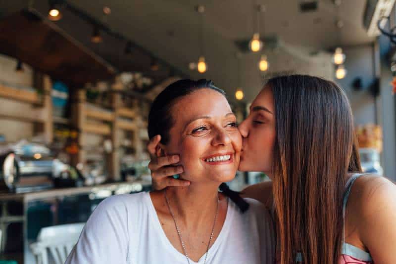 Happy daughter and mom in a nice cafe with copy space on blurred background