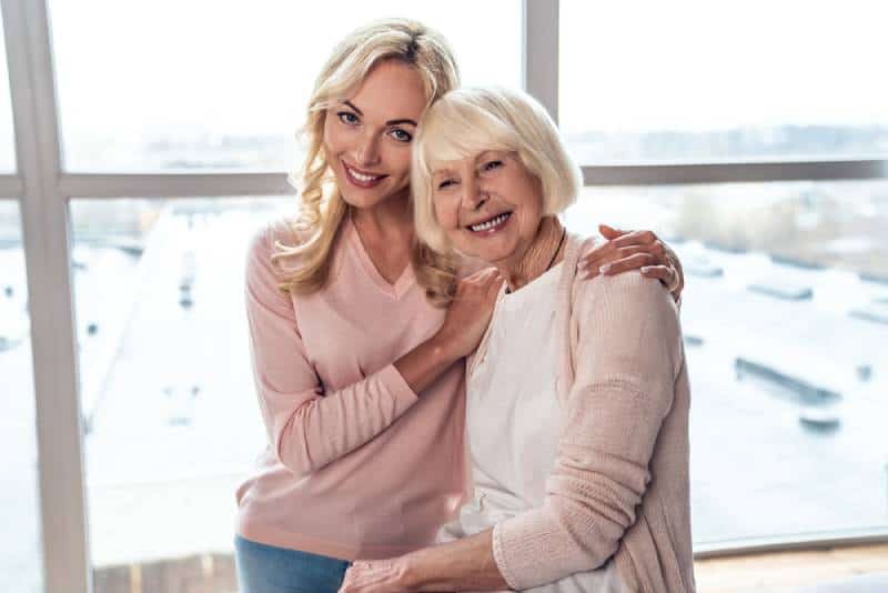  woman and her attractive daughter spending time together and hugging at home 