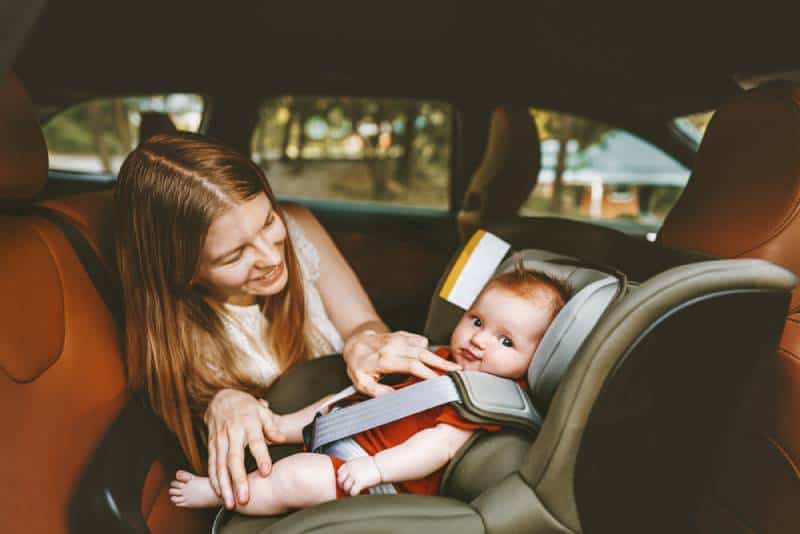 happy mom talking to a baby in a car seat