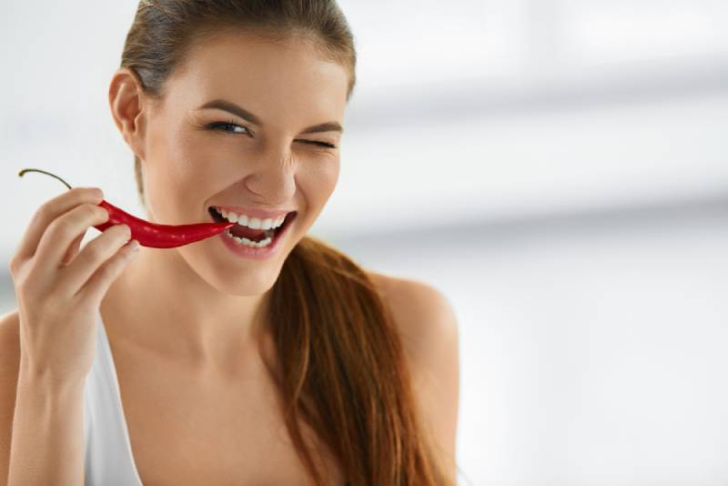 Woman Biting Spicy Hot Red Chili Pepper