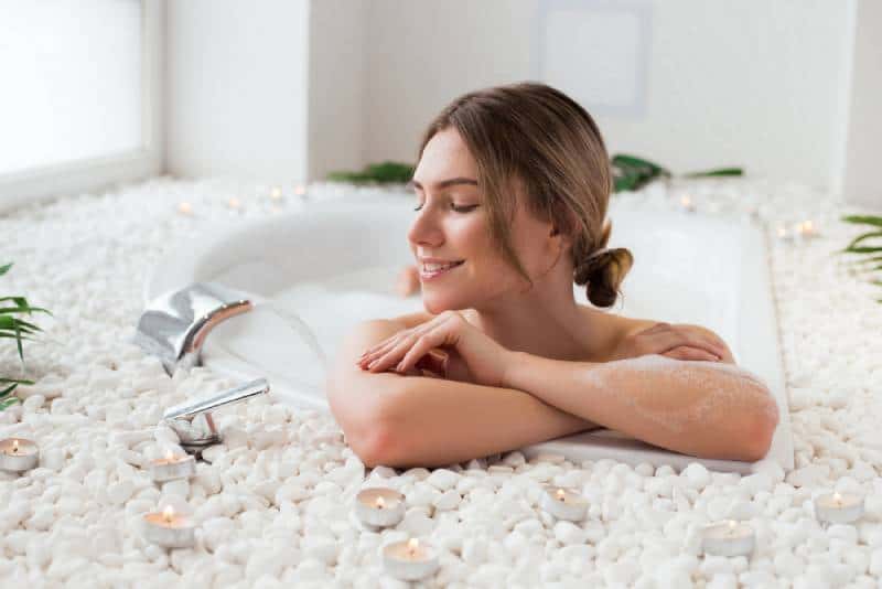 Woman lying in the hot bath with bubbles and having a great spare time