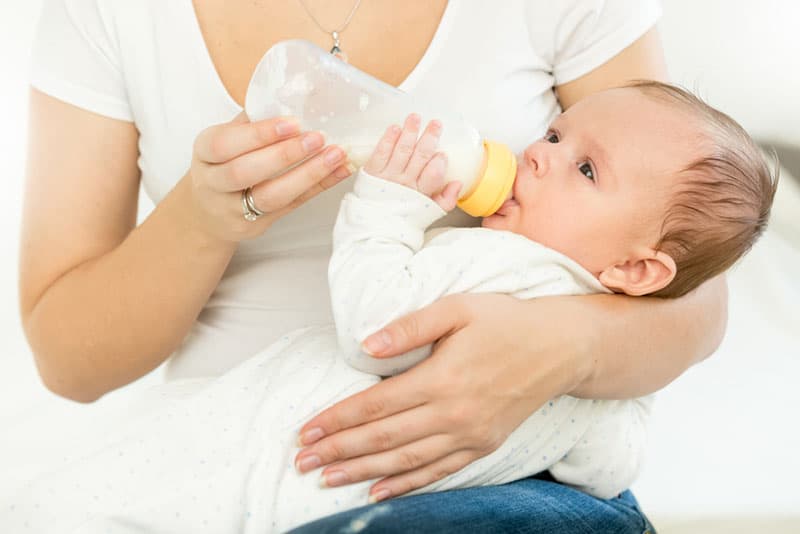 mother feeding her baby with bottle of milk
