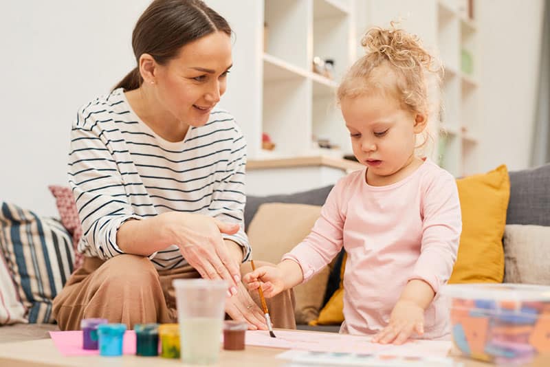 mother teaching daughter how to paint