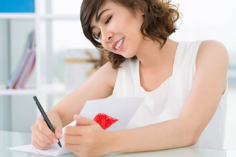 smiling woman writing congratulation card