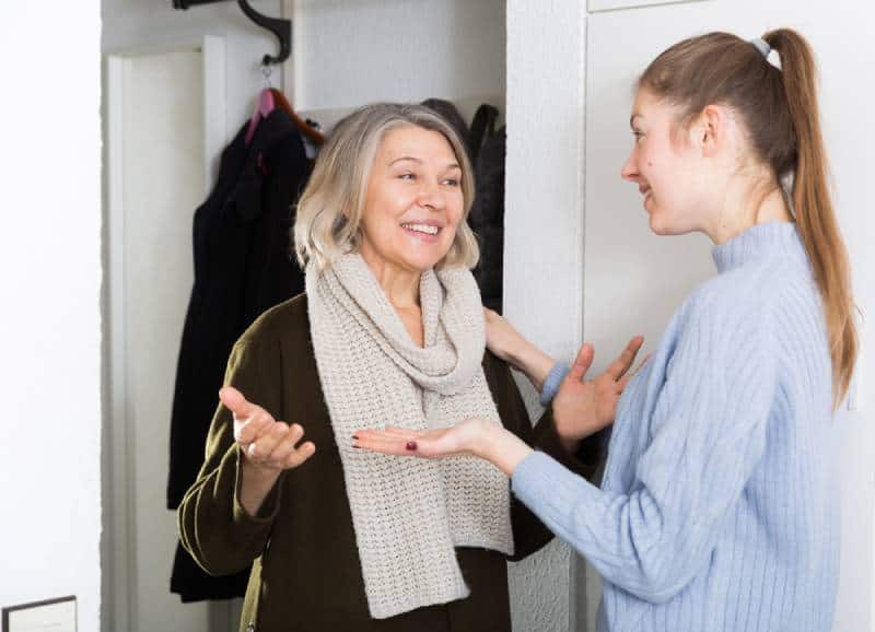 Young and older women having emotional conversation in apartment hallway