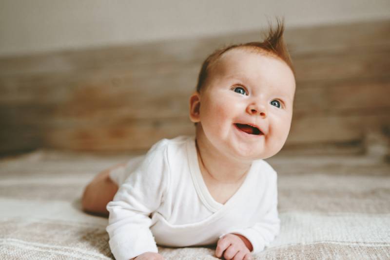  infant baby crawling on bed and smiling 