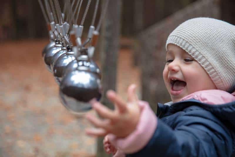 Toddler having fun with a perpetuum mobile at a forrest playground