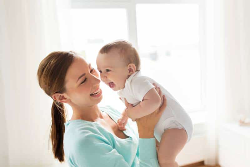 Mom holding baby and smiling indoors