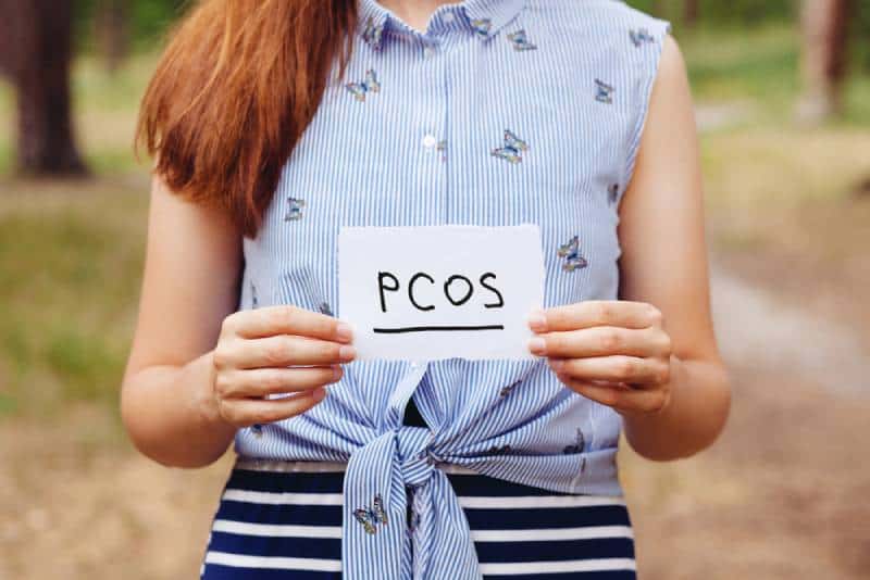 Woman holding pcos sign while standing outside