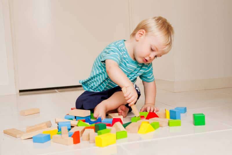 baby boy playing with colorful blocks indoors