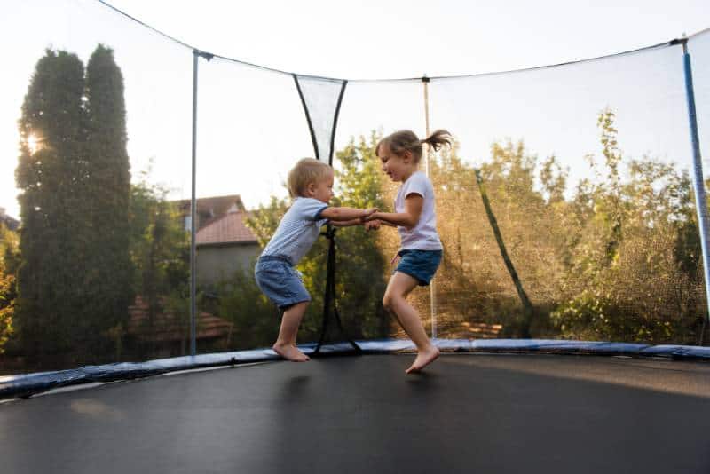Siblings having fun as they jump on trampoline
